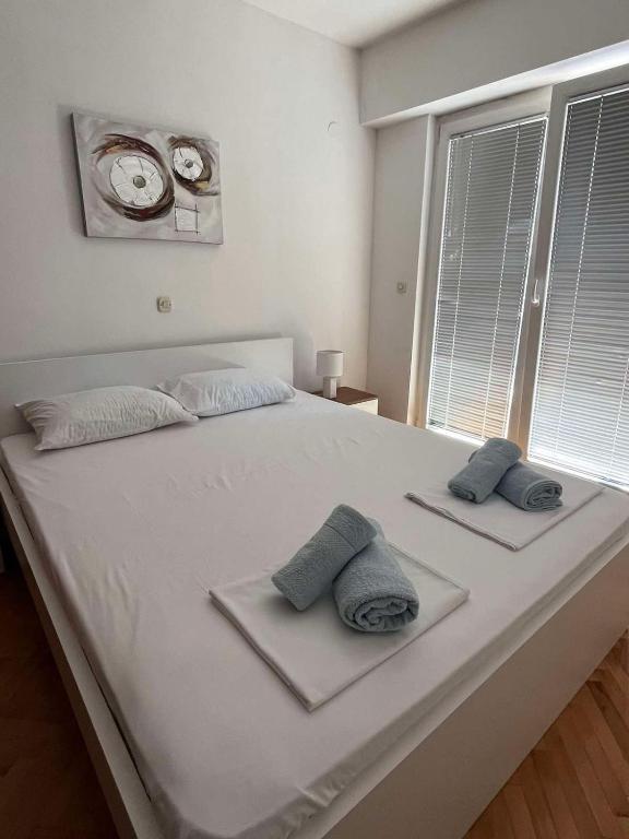 duże białe łóżko z dwiema poduszkami i zegarem w obiekcie Rosana's Apartment w Ochrydzie