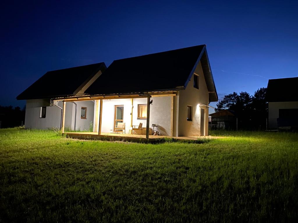 a small white house with a black roof in a field at Domek Ewa in Macharce