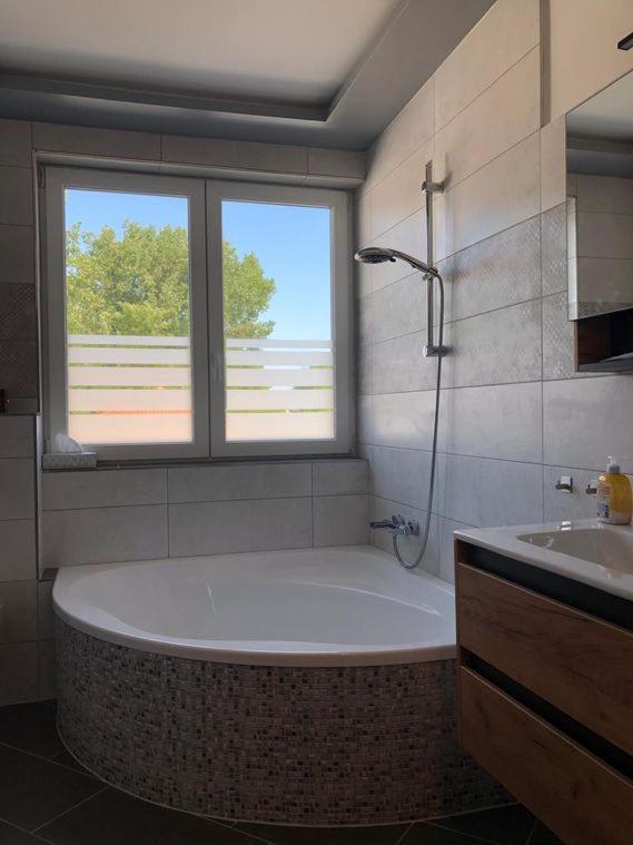 a bathroom with a tub and a window and a sink at Schicke Apartments in Messenähe in Hannover