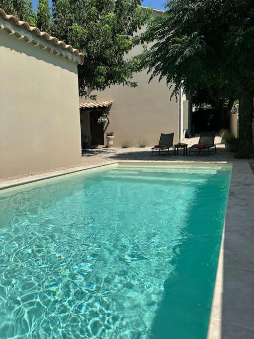 une piscine avec deux chaises à côté d'une maison dans l'établissement Logement Cairanne, à Cairanne