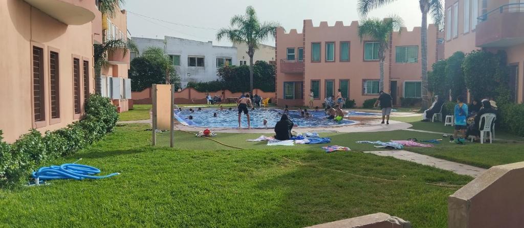 un grupo de personas sentadas en el césped cerca de una piscina en Duplex a sidi Bouzid pour famille - Luxury Mini Villa with Swimming Pool, en Sidi Bouzid