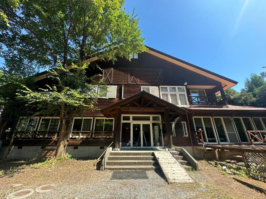 una casa in legno con un albero di fronte di Hakuba Third Place Lodge a Hakuba