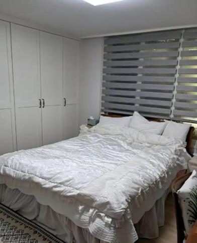 a bedroom with a bed with white sheets and a window at Chanel House Seoul in Seoul