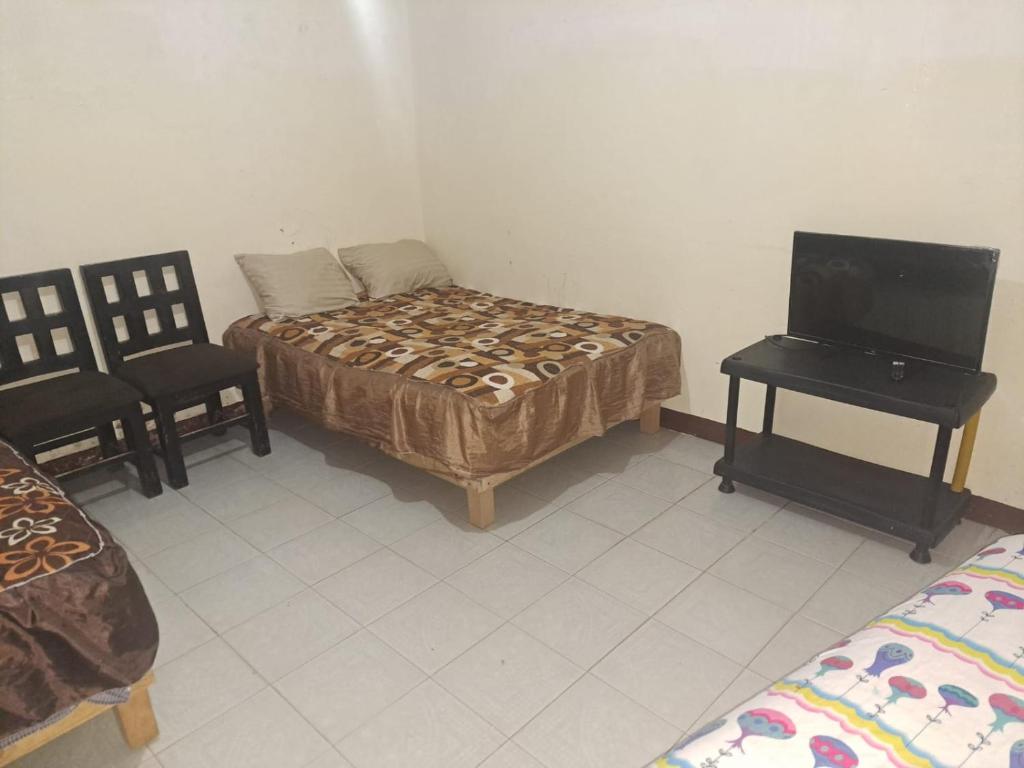 Habitación con 1 cama, TV y 2 sillas. en Hotel CASA ORTIZ, en Zorita