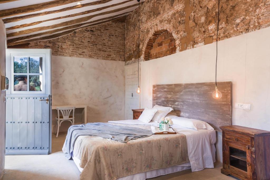 - une chambre avec un lit et un mur en briques dans l'établissement Balneario Aguas de Villaharta, à Villaharta