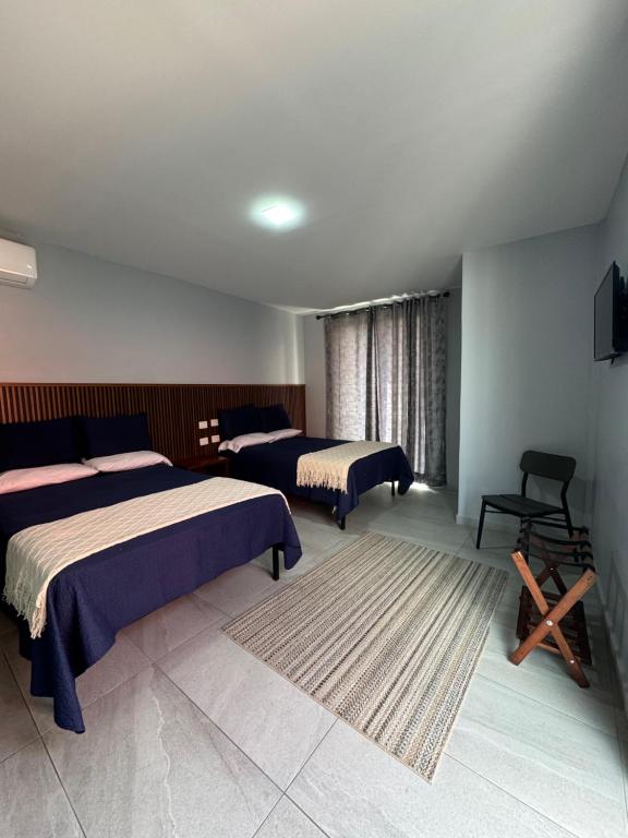 a bedroom with two beds and a chair in it at Hotel Santa María Inn in San Juan de los Lagos