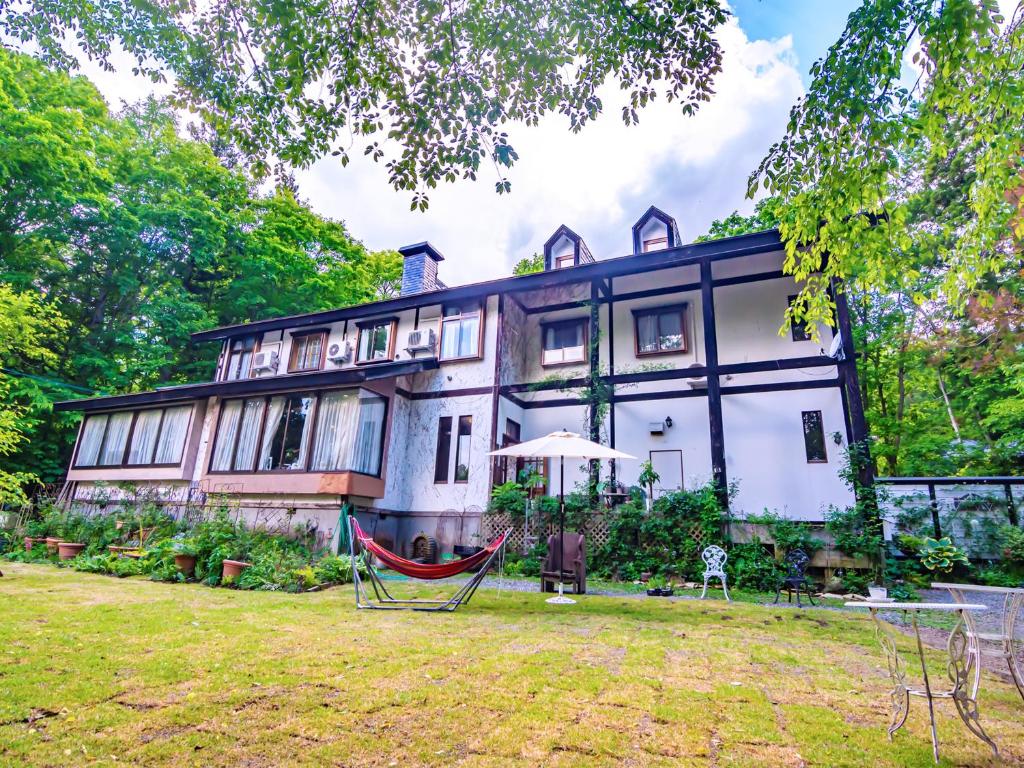 a large house with a hammock in front of it at Garden Pension Obergurgl in Hakuba