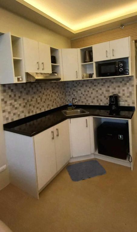 a kitchen with white cabinets and a black counter top at Avida Davao Condos, downtown CM Recto Avenue, Davao City in Davao City