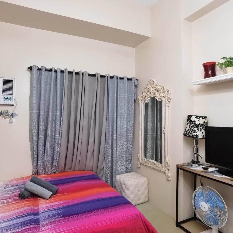 a bedroom with a bed and a tv and a window at Avida Davao Condos, downtown CM Recto Avenue, Davao City in Davao City