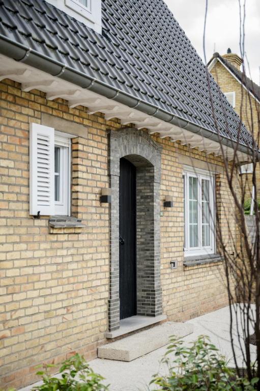a brick house with a black door and two windows at Vakantievilla 3 Beaufort in Nieuwpoort