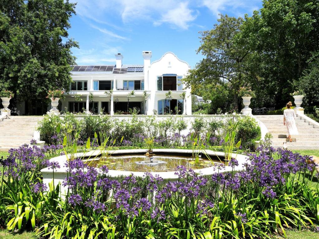 a garden with purple flowers in front of a white house at Constantia Klein in Cape Town