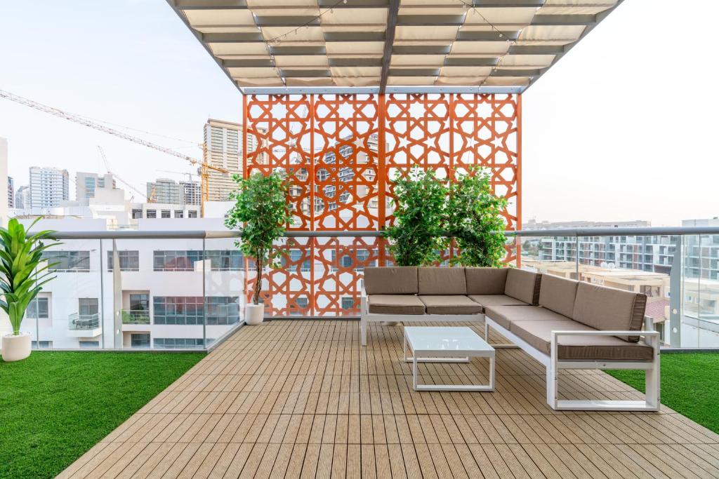 eine Dachterrasse mit einem Sofa und Pflanzen auf einem Gebäude in der Unterkunft Upgraded Designer-crafted Studio in JVC with Massive Terrace in Dubai