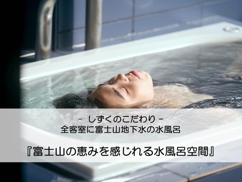a woman in a bath tub with her head in the water at Mt Fuji View and Private Sauna Ryokan Shizuku in Yamanakako