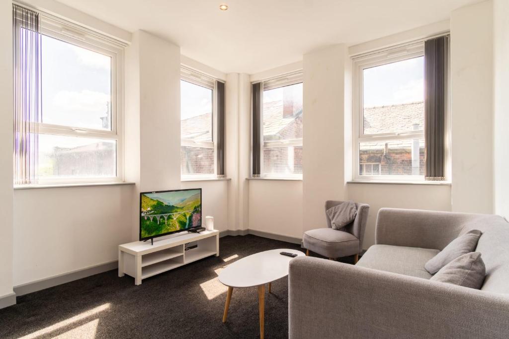 a living room with a couch and a tv at Bright 2 Bed Apartment in Central Blackburn in Blackburn
