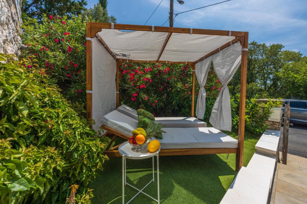 a bed with a canopy in a garden with flowers at Amarie in Dramalj