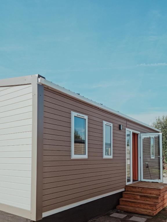 a small house with a wooden siding and windows at Super Cordelia - Camping Belle-Vue in Berdorf