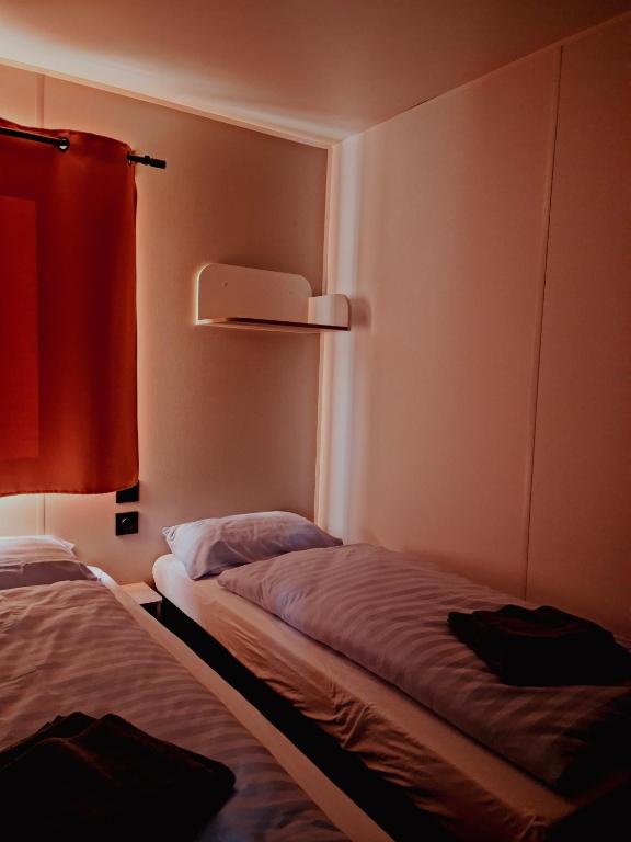 a small room with two beds and a red curtain at Super Cordelia - Camping Belle-Vue in Berdorf