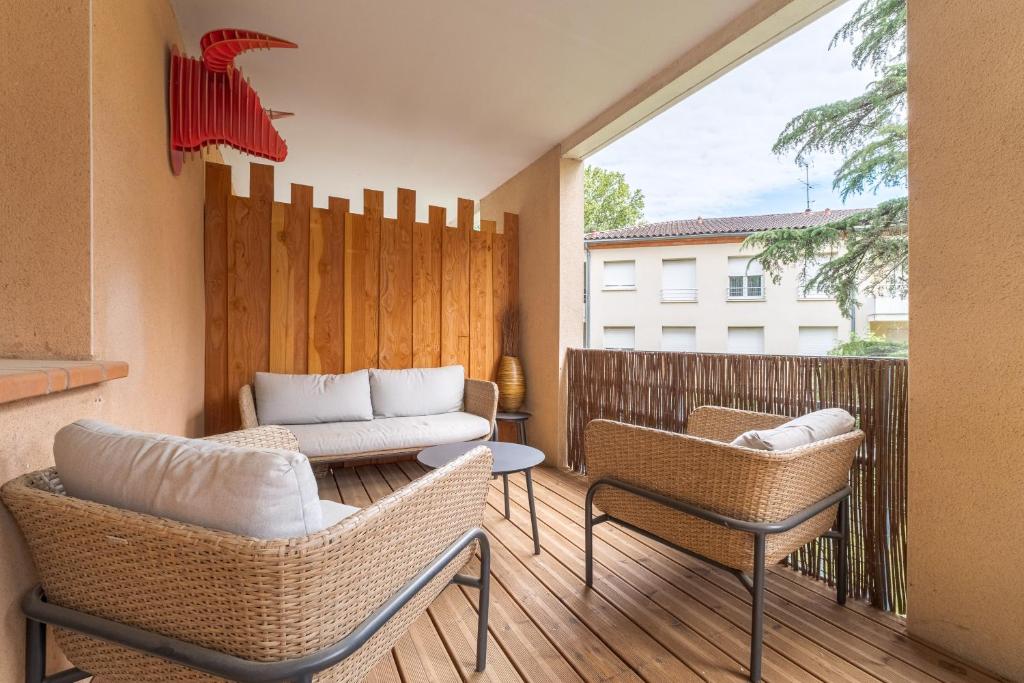 un patio avec deux chaises et un canapé sur une terrasse dans l'établissement Le Cocon d'Adamille - Appt avec piscine partagée, à Tournefeuille