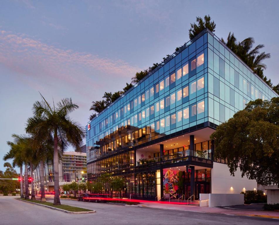 un edificio de cristal alto con una palmera delante de él en citizenM Miami South Beach, en Miami Beach