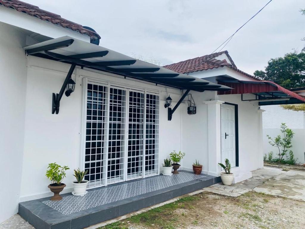 a white house with a blue awning at Golf Avenue Homestay Kota Bharu in Pengkalan Cepa