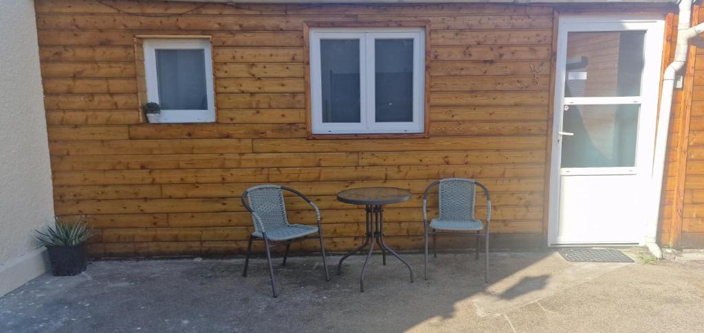 d'une terrasse avec 2 chaises, une table et 2 fenêtres. dans l'établissement Studio Cerf, quartier marais, terrasse rez de chaussé, jardin accessible, matelas confortable, à Bourges