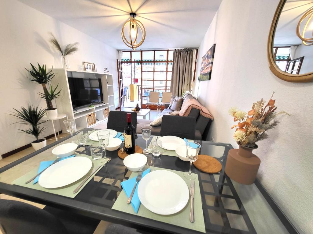 a living room with a dining room table with white plates at Apartamento Claudia en Lago Santiago con piscina in Puerto de Santiago