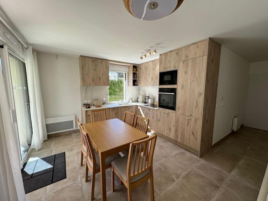 Il comprend une cuisine avec une table et des chaises en bois. dans l'établissement Jardin Secret A04, à Antibes