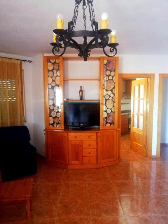 a living room with a tv and a chandelier at Casa Serrano in Letur