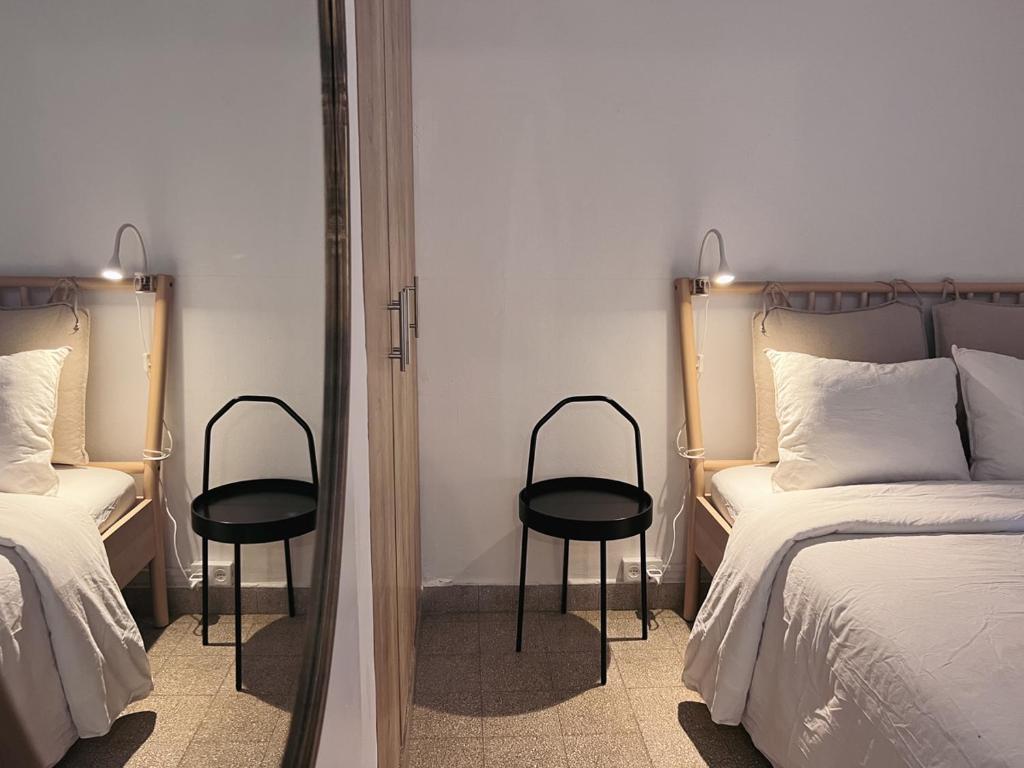 a bedroom with two beds and two black chairs at הצימר של יהושע in Ein Gedi