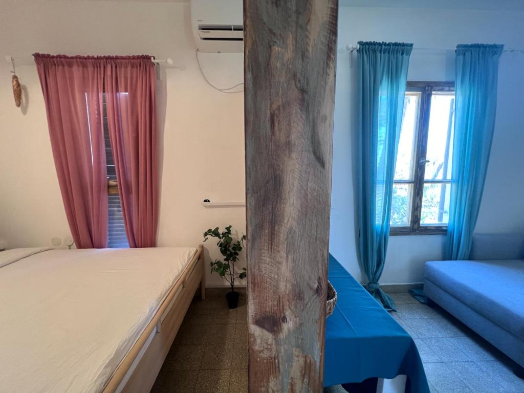 a bedroom with two beds and blue curtains at הצימר של יהושע in Ein Gedi