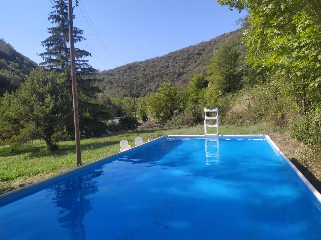 a blue swimming pool with a ladder and a chair at La Grenouille in Valleraugue