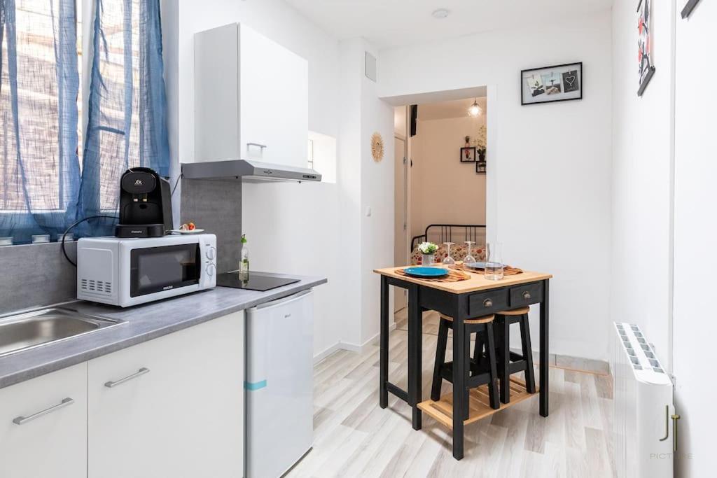 une petite cuisine avec une table et un micro-ondes dans l'établissement Joli studio confortable, à Saint-Quentin