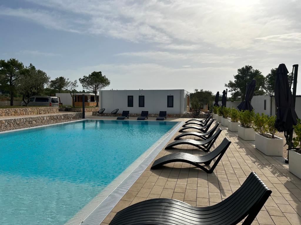 a row of chairs sitting next to a swimming pool at Holiday Home Ahil 10 in Pakoštane