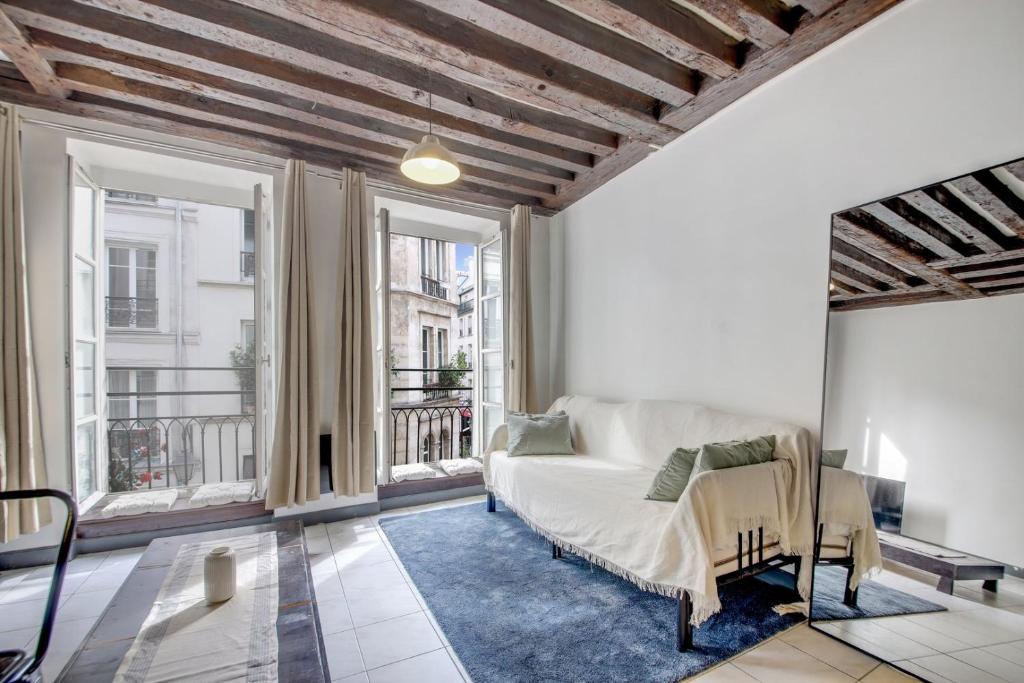 - un salon avec un canapé et de grandes fenêtres dans l'établissement Paris Marais Lombards, à Paris