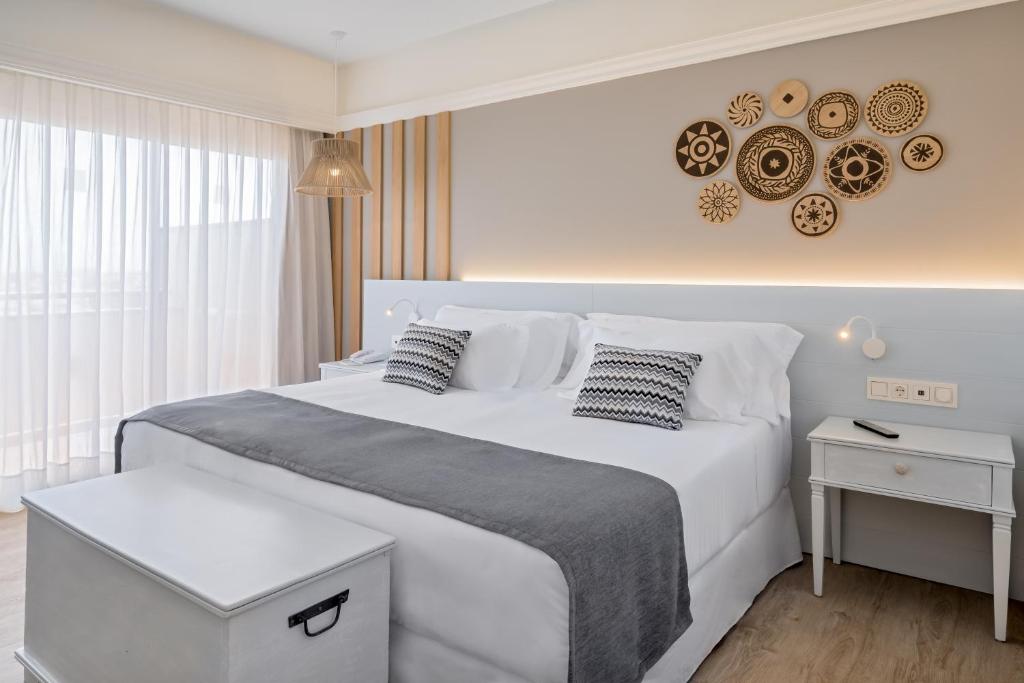 a white bedroom with a large white bed with pillows at Barceló Corralejo Bay - Adults Only in Corralejo