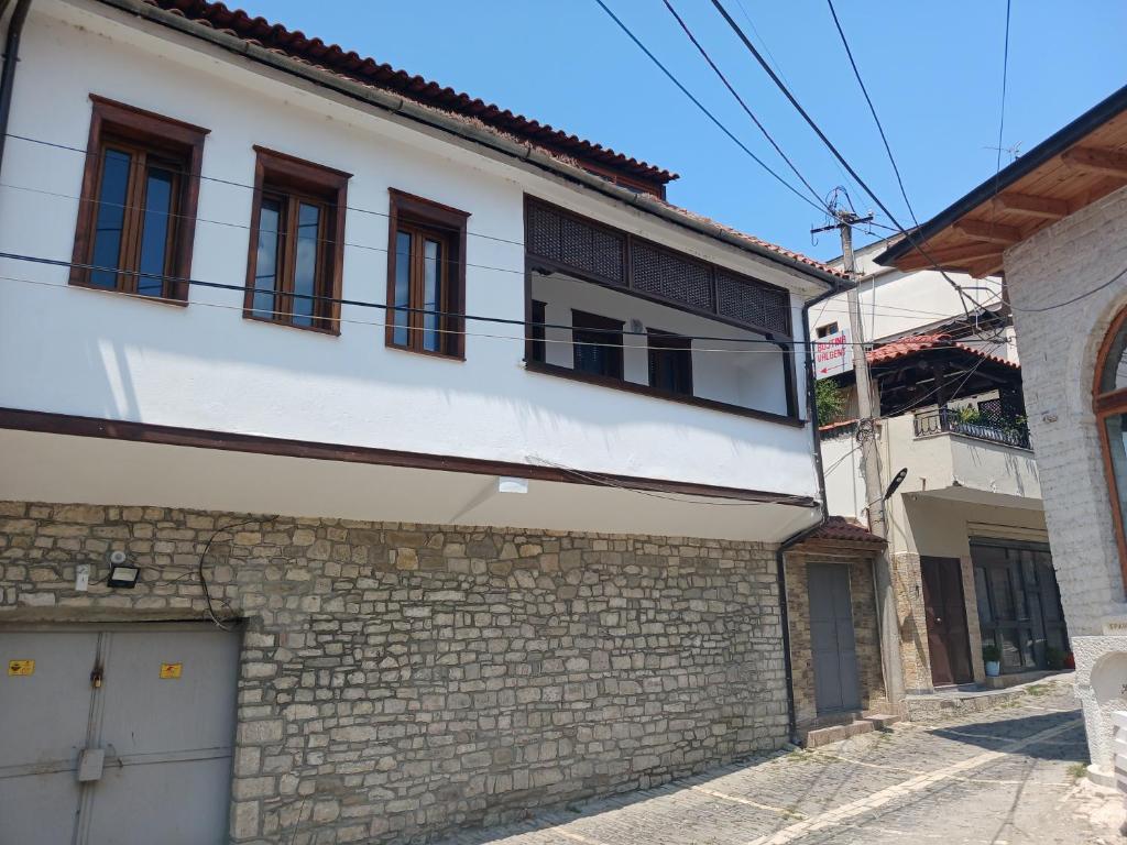 a white building with windows and a brick wall at Bujtina Valgent in Berat