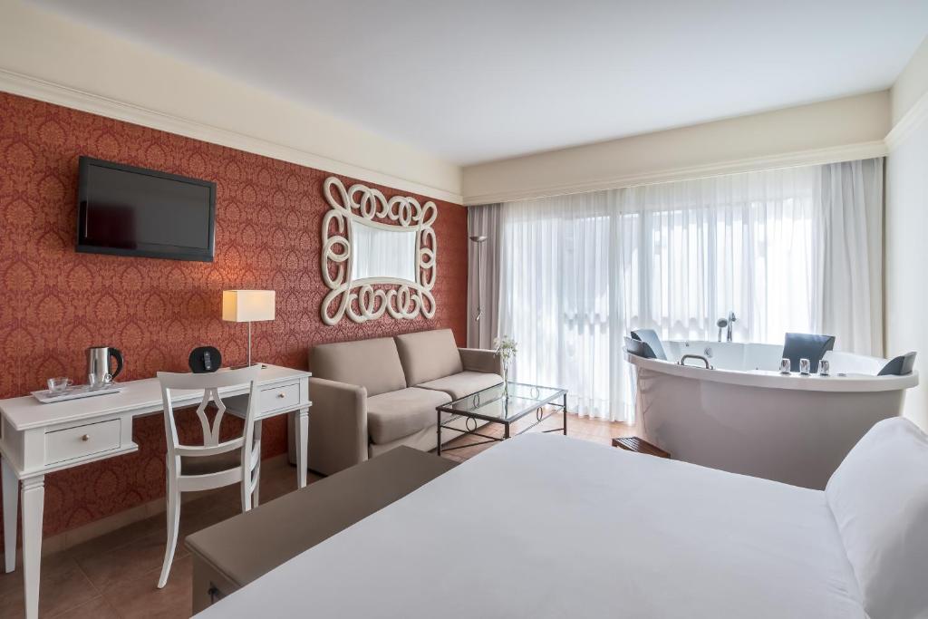 a hotel room with a bed and a bathtub at Barceló Corralejo Bay - Adults Only in Corralejo