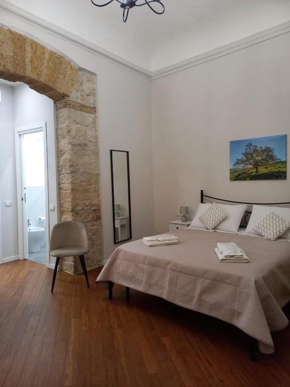 a white bedroom with a large bed and a chair at Residenza del Massimo in Palermo