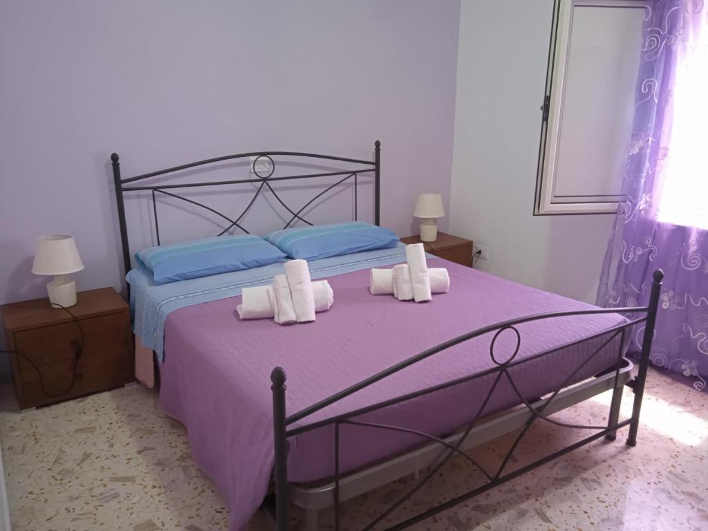 una camera da letto con letto con lenzuola viola e cuscini blu di B&B Porta di Suso Camerota a Camerota