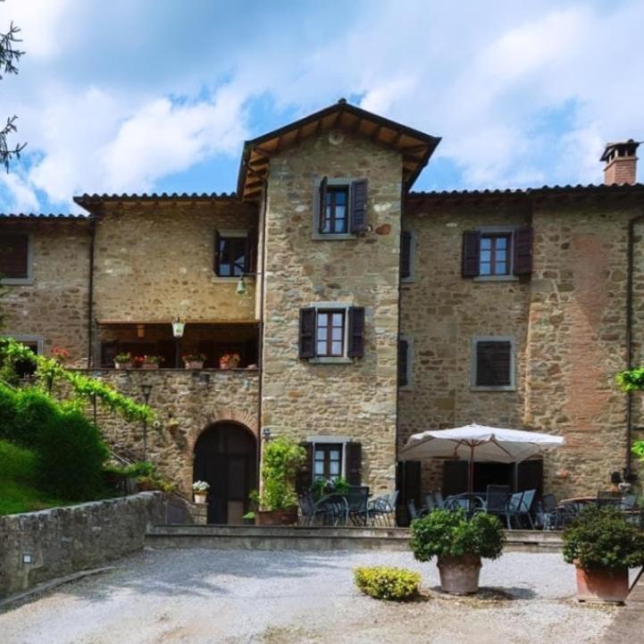 a large stone building with an umbrella in front of it at Agriturismo L'Essiccatoio in Lisciano Niccone