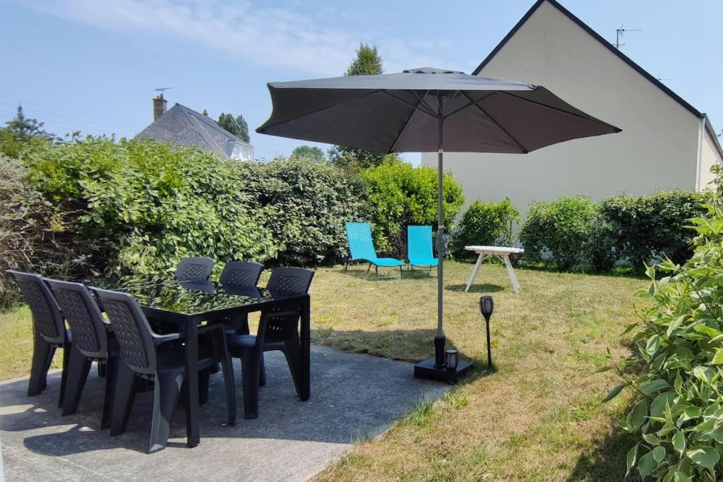 une table noire avec des chaises et un parasol dans l'établissement Chez Irène & Alan - Maison Pila, à La Fresnais