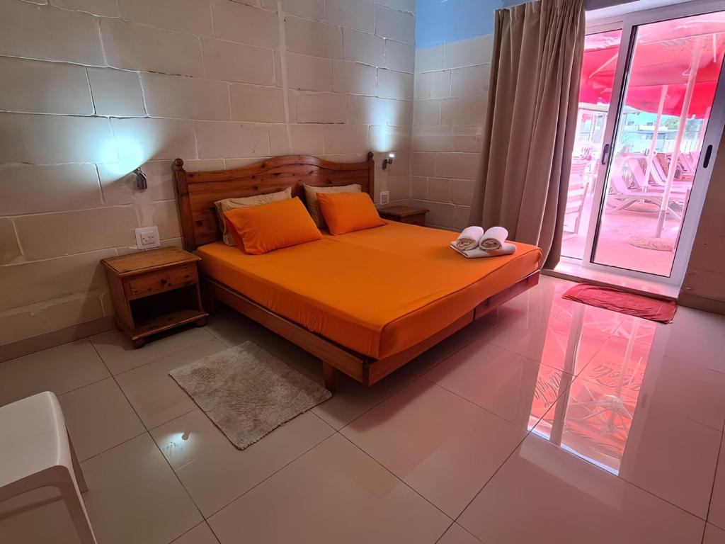 a bedroom with a bed with orange sheets and orange pillows at Sensi Hotel in Marsaskala