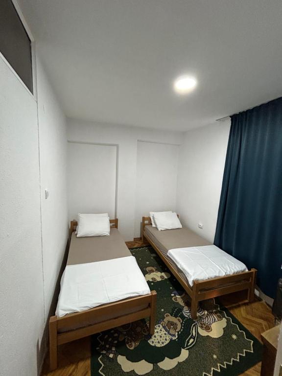 - 2 lits dans une petite chambre avec des rideaux bleus dans l'établissement Vintage Apartman, à Strumica
