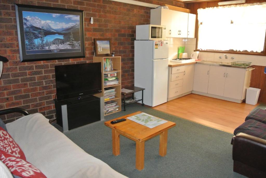a living room with a couch and a table and a kitchen at Kalamunda 2 in Bright