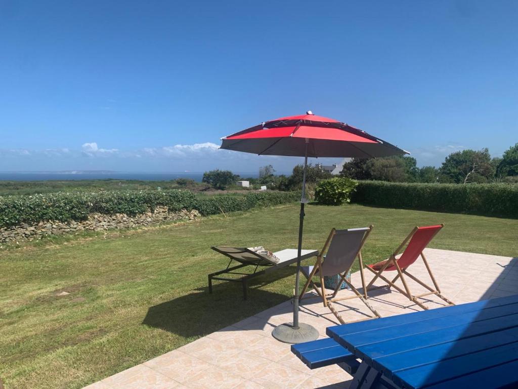 a table and two chairs under an umbrella on a patio at Magnifique Maison face à l'Océan - Pointe du RAZ in Penharn