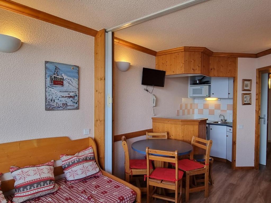 Cette petite chambre dispose d'une cuisine, d'une table et de chaises. dans l'établissement Studio agréable avec accès direct aux pistes et coin montagne - FR-1-181-2583, à Aime La Plagne
