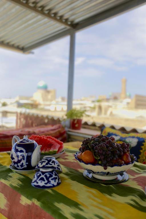 a table with two plates of fruit on a table at Sarrof Guest House in Bukhara