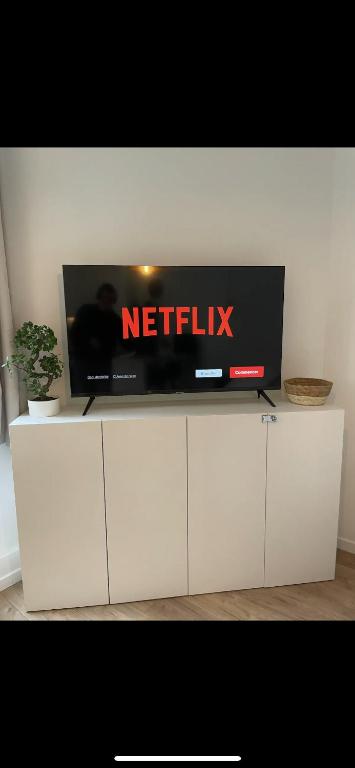 une télévision assise au-dessus d'un meuble blanc dans l'établissement Suite moderne au cœur du 8e, à Paris