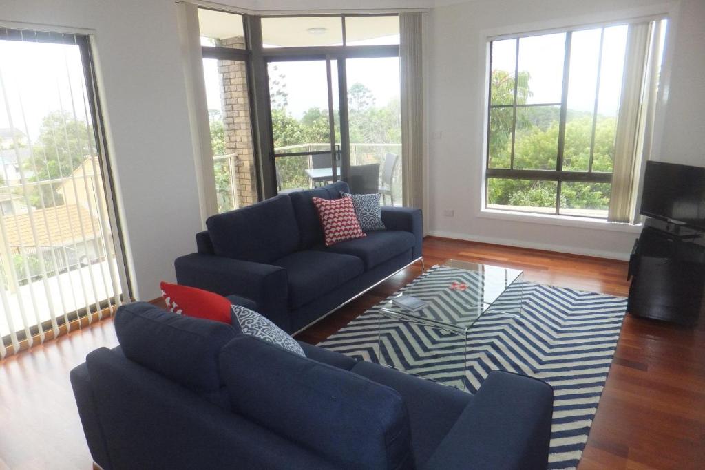 a living room with two blue couches and a rug at Ocean Retreat in Nambucca Heads