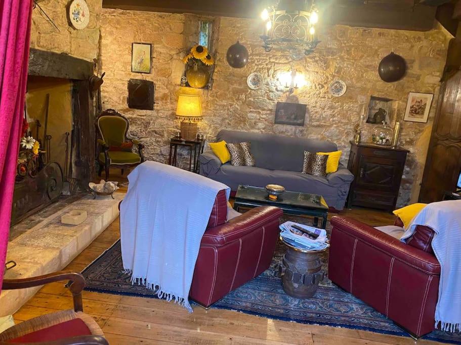 un salon avec des canapés et un mur en pierre dans l'établissement Maison historique en Perigord, à Belvès